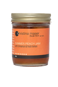 Summer peach jam in clear glass mason jar with orange label and gold metal lid.