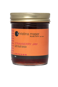 Classic strawberry jam in clear glass mason jar with orange label and gold metal lid.