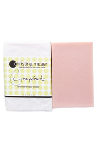 Grapefruit vegan bar soap. Soap is a pale pink and wrapped in white paper with label with light green dot accents.